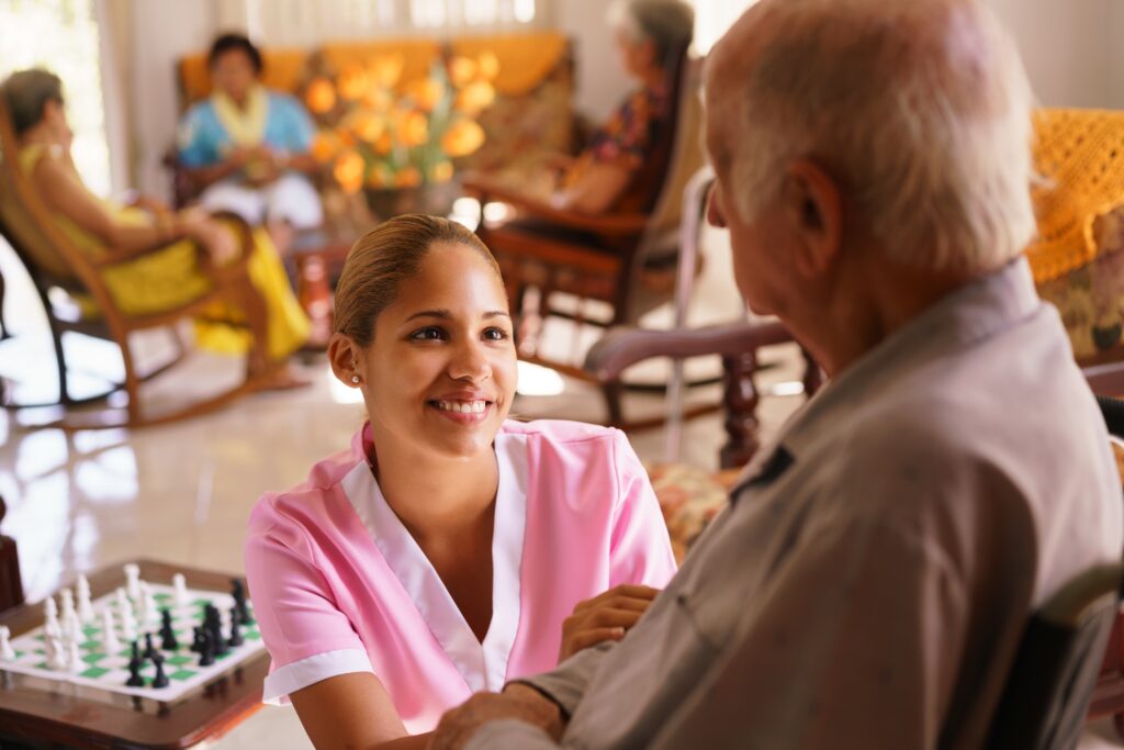 Female carer in aged care home looking at elderly male resident