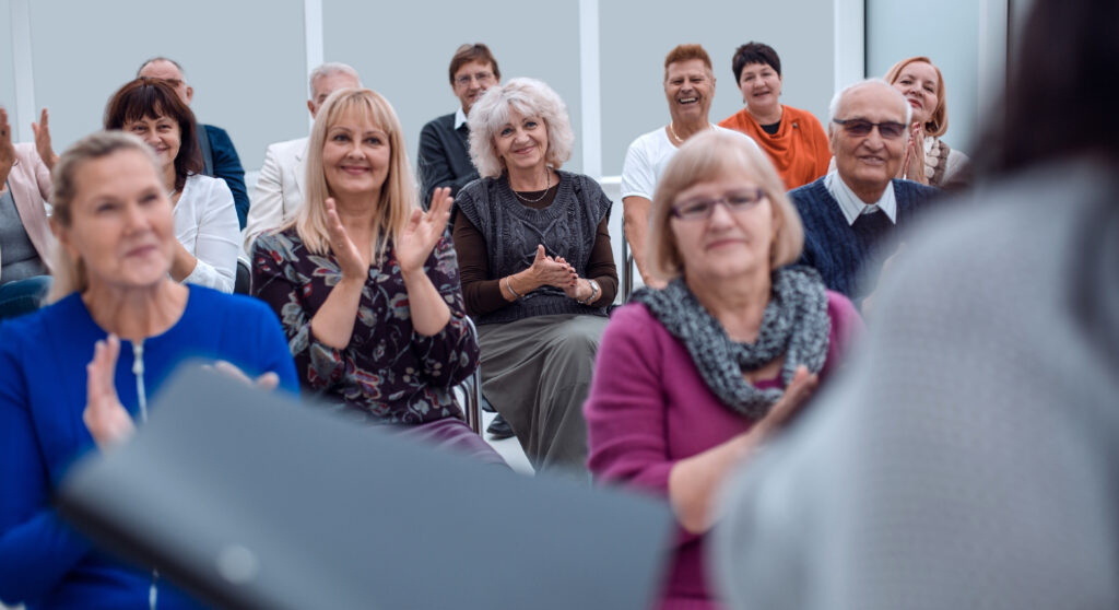 Room of people clapping at a presenter