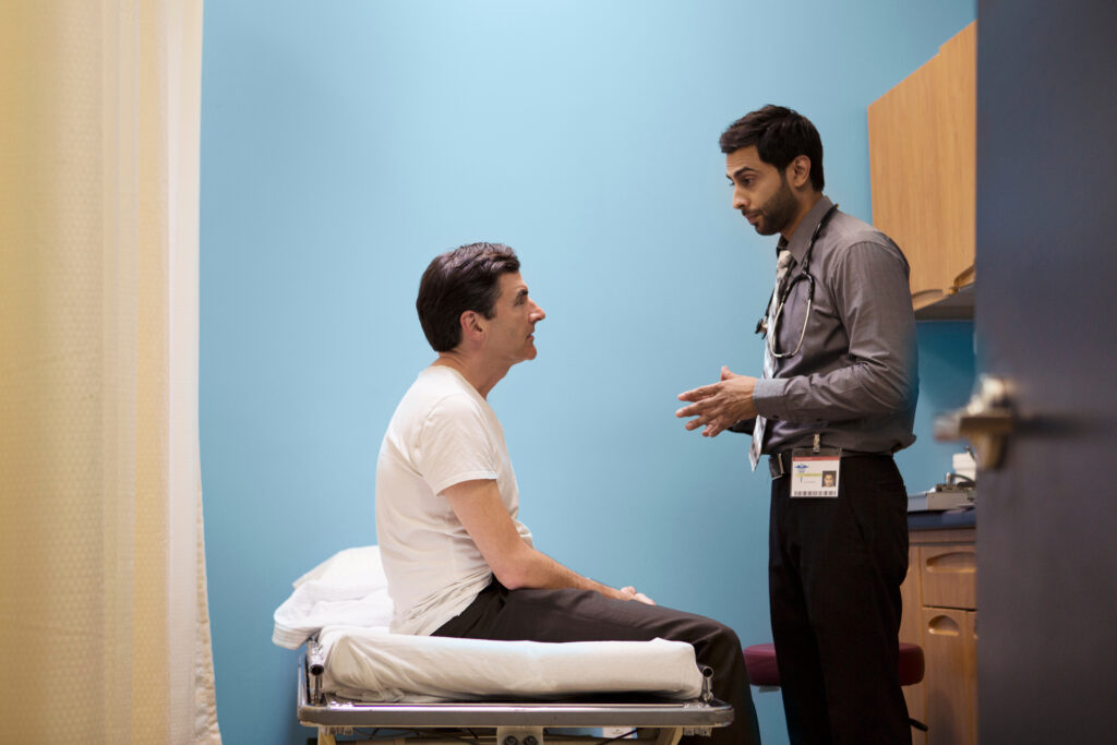 South asian doctor speaking to patient who is seated on a bed