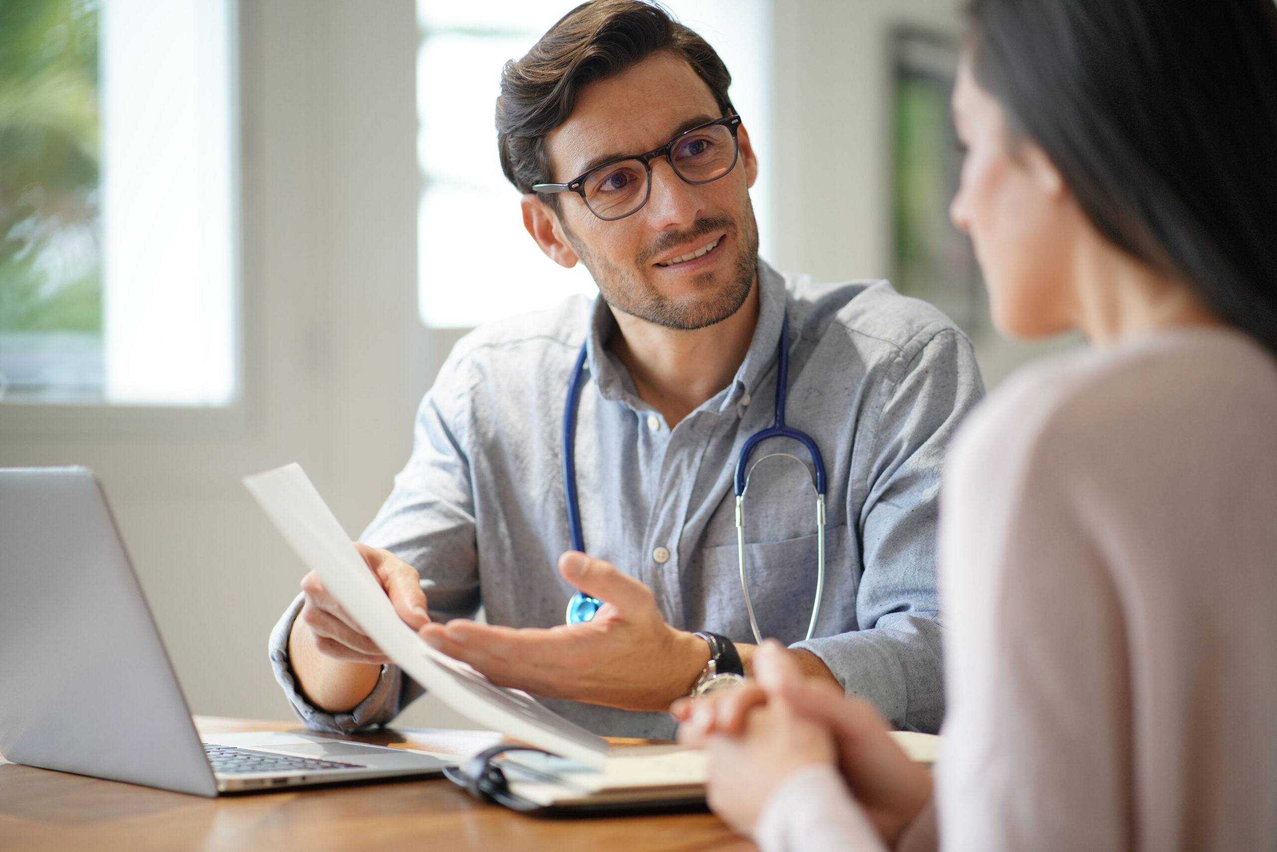 Male GP talking to patient while seated at desk