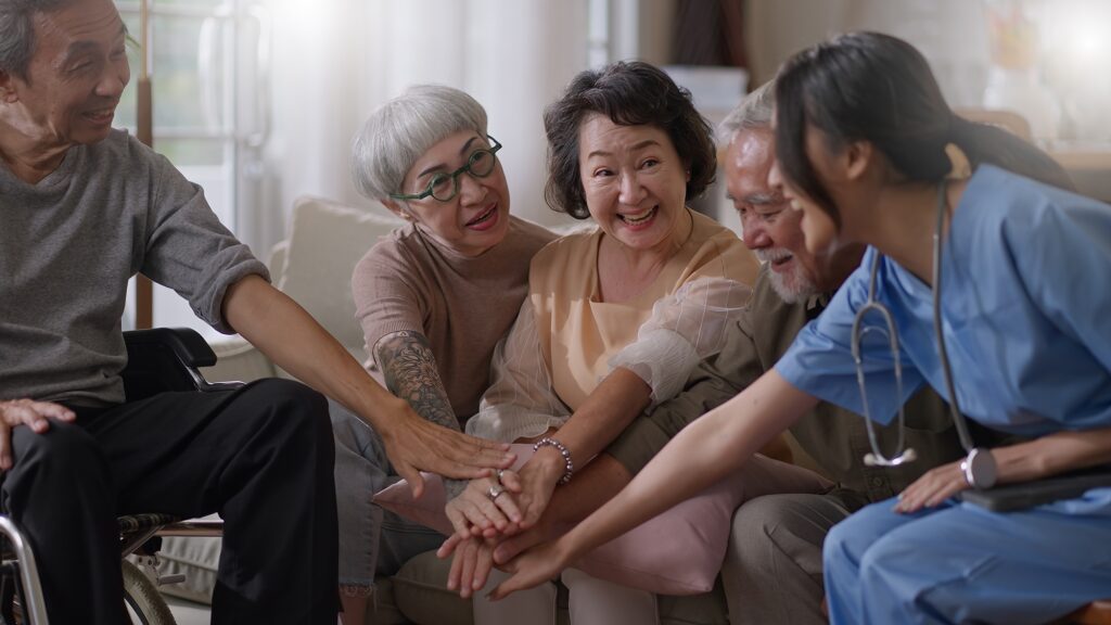 Group of elderly people reaching into a circle to hold hands