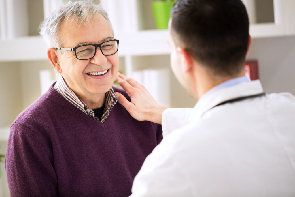 Older male at doctor clinic smiling at doctor