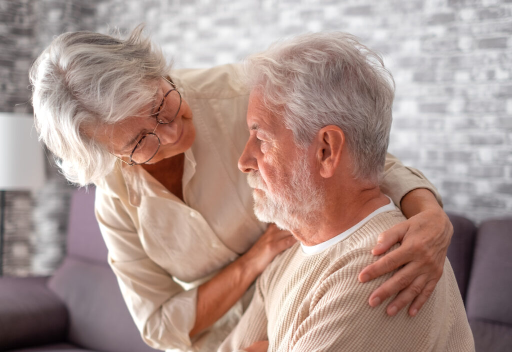 Elderly male looking sad and being supported by an elderly woman