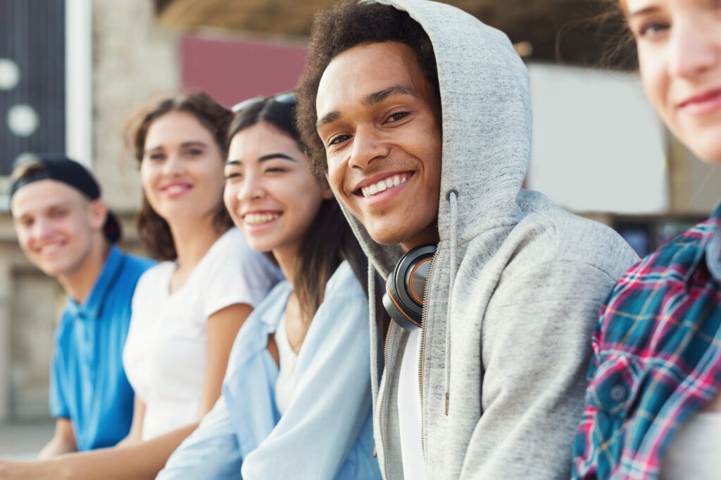 A row of young people smiling at the camera with a male teen in focus