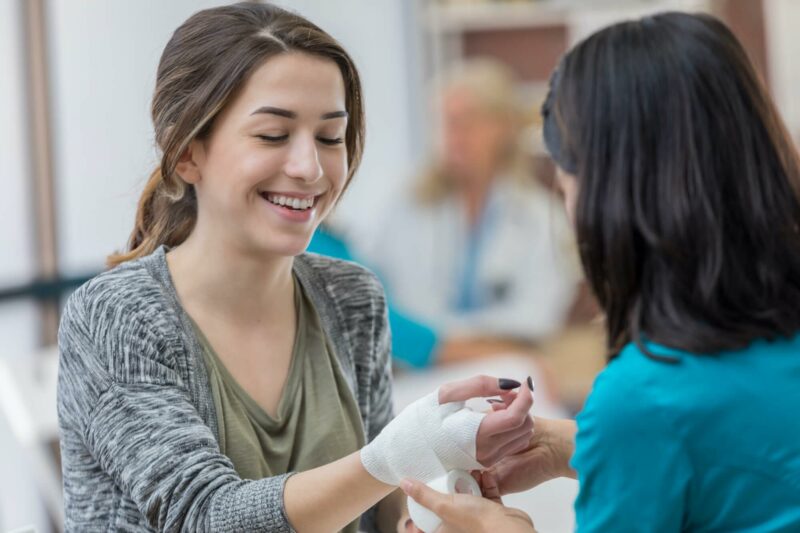 Young woman having wrist bandaged by a doctor