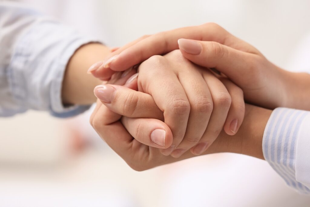 Two hands holding, one is positioned on top of the other