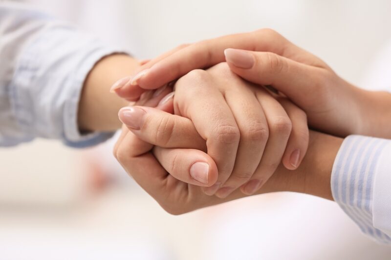 Two hands holding, one is positioned on top of the other
